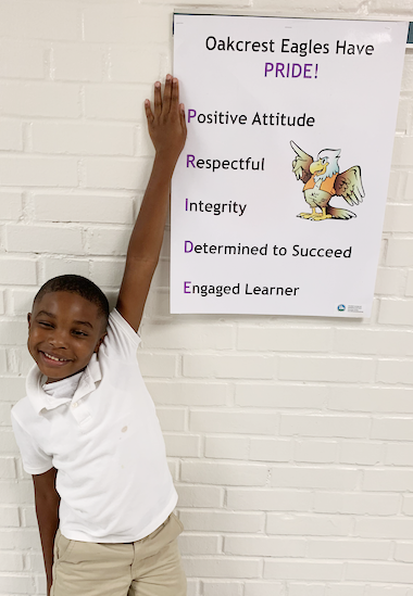 Student pointing to a banner with the Oakcrest PRIDE Pledge